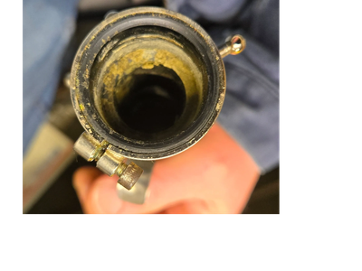 Close-up of a rusty pipe clamp on a corroded cylindrical object.