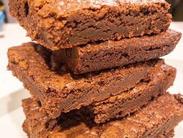 Image of moist brownies stacked on top of each other on a platter.
