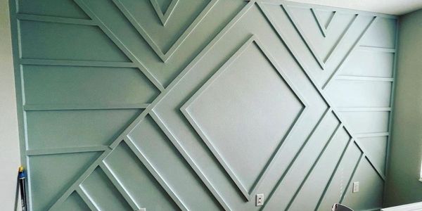 Geometric accent wall with diamond shapes and lines painted in muted green.