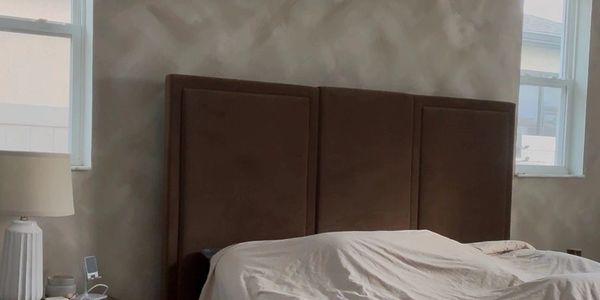 Cozy bedroom with large bed, neutral tones, and natural light from two windows.