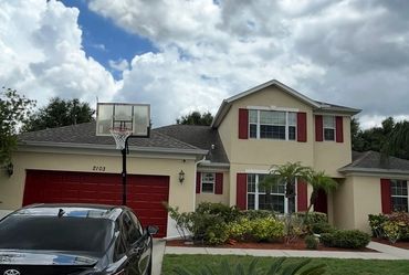 Suburban house with red shutters and a basketball hoop in the driveway.