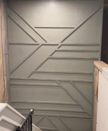 Geometric patterned accent wall painted gray in stairwell.