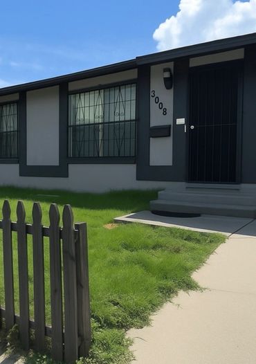 Modern house entrance with black door and green lawn.