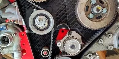 Close-up of a timing belt system in an engine with gears and pulleys.