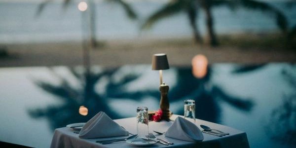 Romantic dinner setup with a poolside view at dusk.