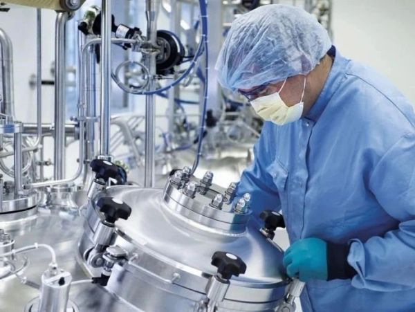 Scientist in protective gear operating lab equipment in a sterile environment.