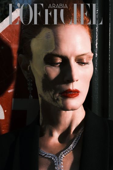 Close-up portrait of a woman with red hair, red lipstick, and elegant jewelry on L'Officiel Arabia cover.