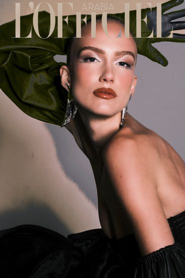 Elegant model posing with green leather gloves and bold makeup on L'Officiel Arabia cover.