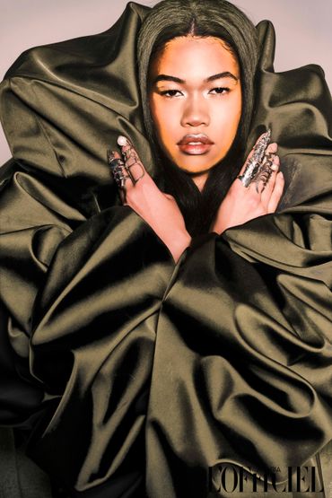 Model wrapped in luxurious fabric with statement rings, exuding bold elegance.