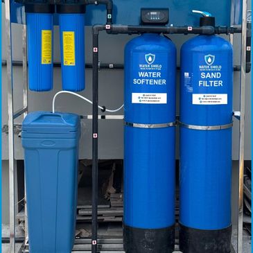 Blue water softener and sand filter system installed indoors.