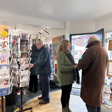 People browsing and chatting inside a cozy art and card shop.