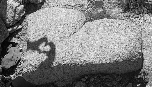 Shadow of hands forming a heart on a heart shaped rock.