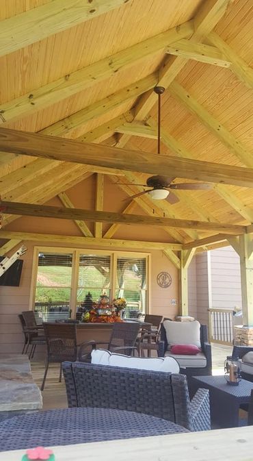 Cozy outdoor seating area with wooden ceiling and ceiling fan.
