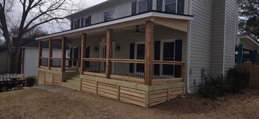 Newly built wooden porch with black railings on a suburban house.