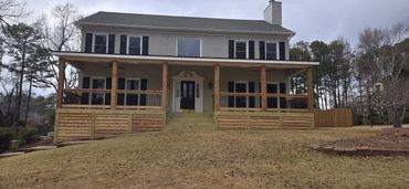 Two-story house with a wooden porch and stairs.