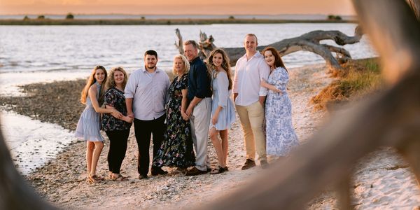 Sherri's family of 8 smiling on a beach with driftwood around them