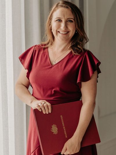 Woman in red dress holding a marriage register.