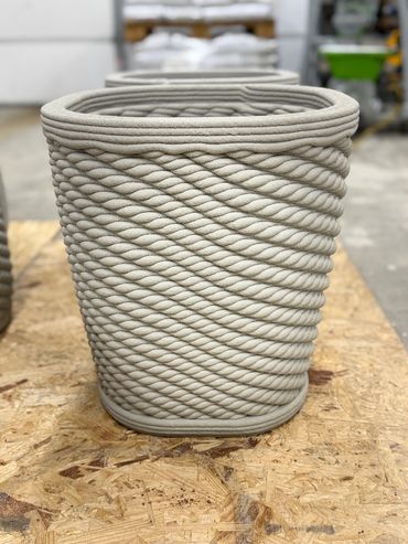 A beige basket with a twisted rope pattern on a wooden surface.