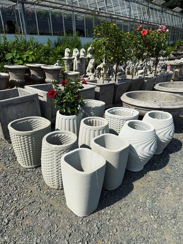 Decorative stone planters and statues displayed outdoors in a garden center.