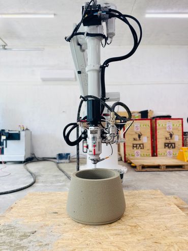 3D printer creating a large concrete pot in an industrial setting.