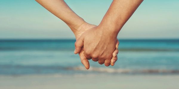 Couple holding hands in front of ocean