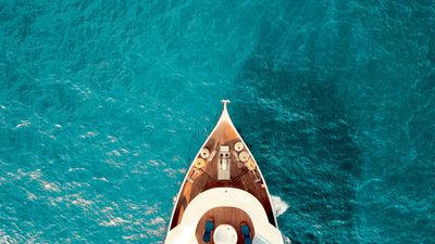 Bow of luxury yacht sailing through crystal clear blue water