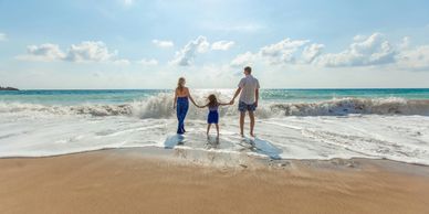 family on a beach in front of waves