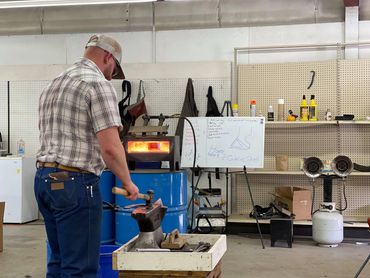 Farrier Student in front of the forge hammering a hot shoe.