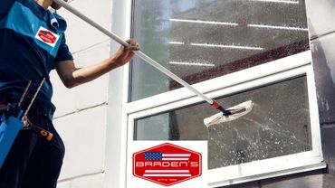 Professional cleaning a large window with a squeegee.