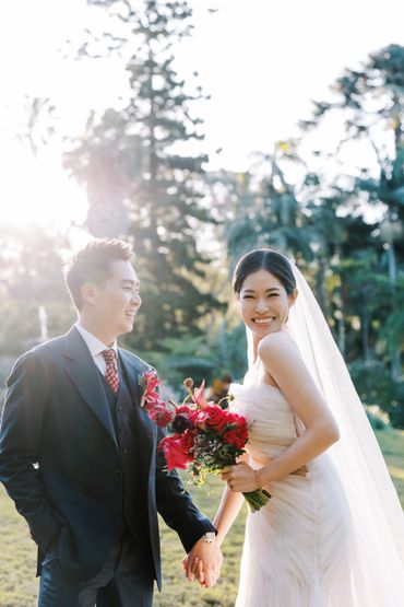 Joyful bride and groom holding hands outdoors on their wedding day.