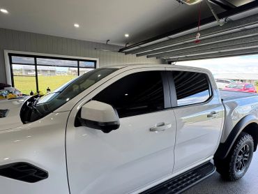 White pickup truck parked inside a garage with tinted windows.