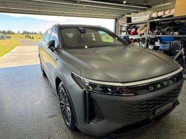 A gray modern SUV parked inside a garage with outdoor scenery visible.