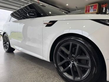 White luxury SUV with black rims parked indoors.