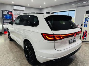 White Volkswagen SUV with sleek black wheels inside a showroom.