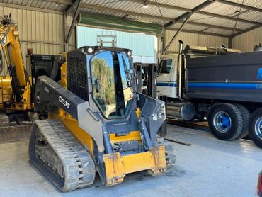 Construction vehicles including a John Deere skid steer loader in a warehouse.
