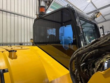 Yellow heavy machinery with black cabin inside a shed.