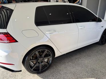 White car with black rims and tinted windows parked indoors.