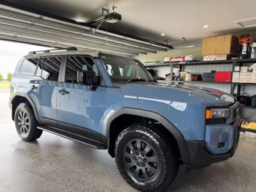 Blue electric SUV parked inside a garage with equipment on shelves.
