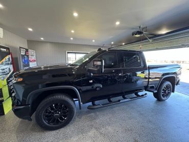 A shiny black pickup truck parked inside a well-lit garage.