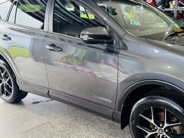 Shiny grey SUV parked inside a garage with organized shelves.