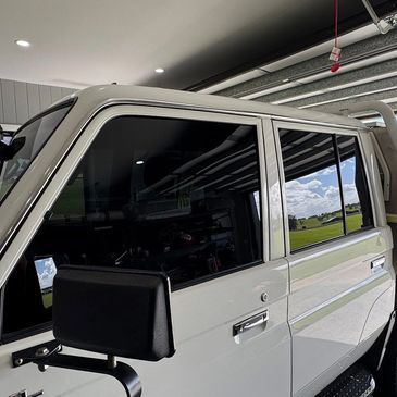 Side view of a white pickup truck with tinted windows in a garage.