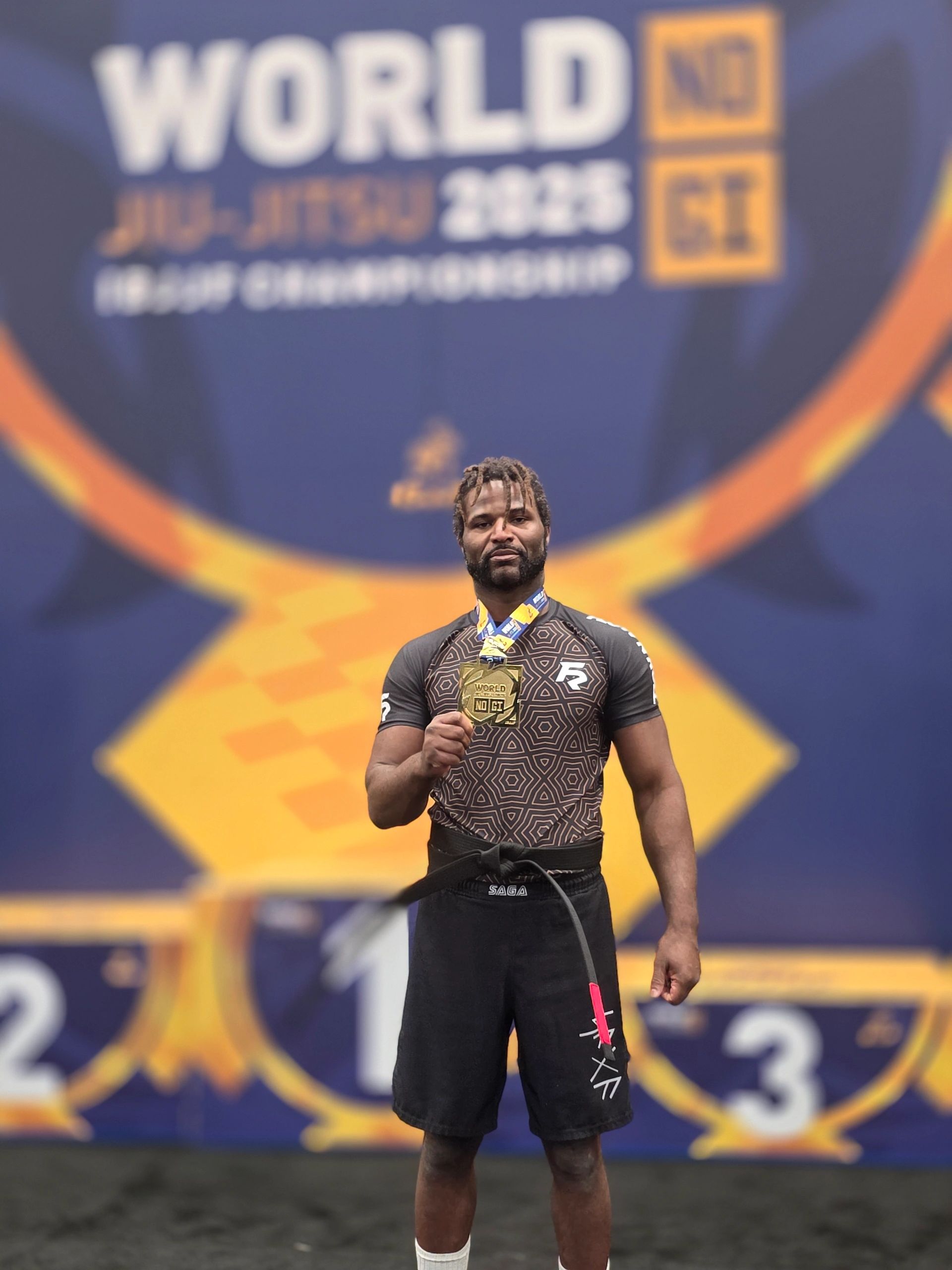 Athlete proudly holding gold medal at 2023 World No Gi Jiu-Jitsu Championship.
