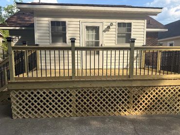 Newly built wooden deck with railing and lattice skirting on a small house.