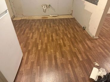 Empty kitchen space with new wood-patterned flooring installed.