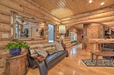 Log cabin seating area. Cozy black leather sofa with fur blanket and throw pillows, and mirror