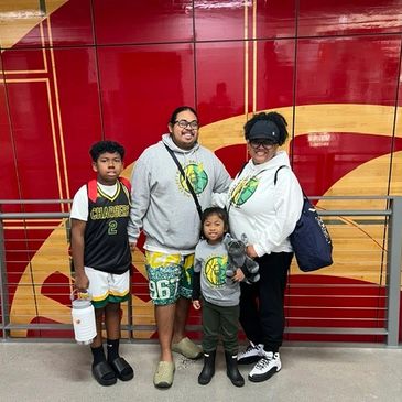 Family of four posing indoors with sports attire and casual wear.