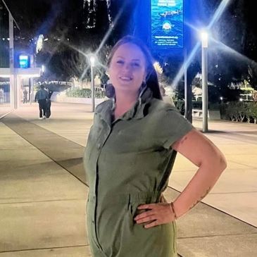 Woman posing outdoors at night with hand on hip in casual outfit.