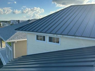 Modern houses with metal roofs under a blue sky with clouds.