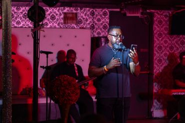 Man reading from a phone while speaking into a microphone on stage.