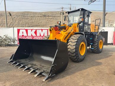 Large yellow front loader parked on a dirt lot near a sign.